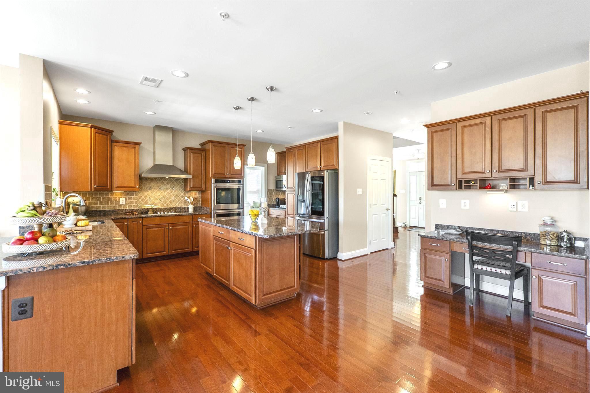18004 Bliss Drive Poolesville, MD 20837 - Photo 17 of 57 a kitchen with stainless steel appliances kitchen island granite countertop a stove a sink a refrigerator cabinets and wooden floor