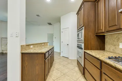 a kitchen with granite countertop a sink stove and refrigerator