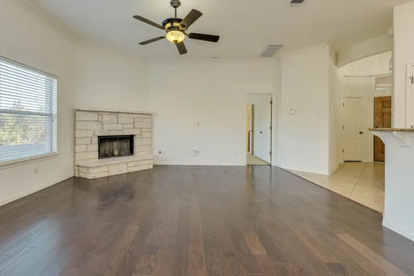 an empty room with wooden floor fireplace and windows