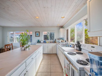 a large white kitchen with a large window a sink and cabinets