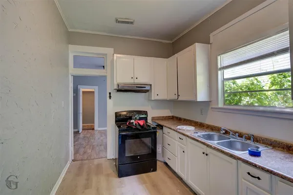 a kitchen with granite countertop a stove a sink and a white cabinets