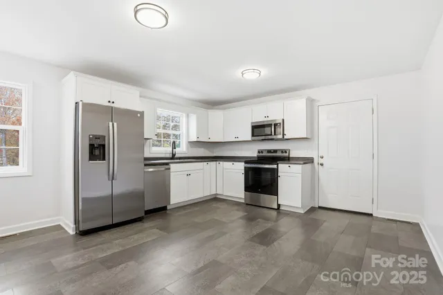 a kitchen with granite countertop white cabinets and stainless steel appliances
