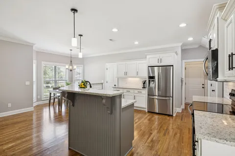 a large kitchen with a center island wooden floor stainless steel appliances and cabinets