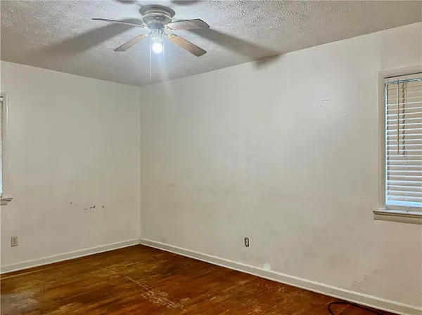 an empty room with a chandelier fan and windows