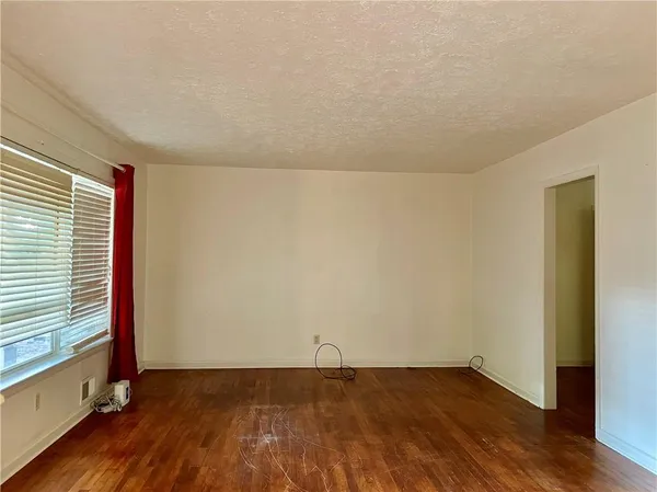 a view of an empty room with wooden floor and a window