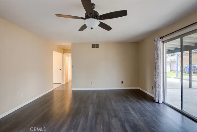 an empty room with wooden floor fan and windows