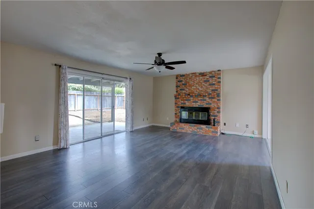 an empty room with wooden floor fireplace and windows