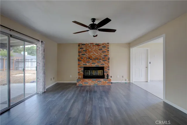 an empty room with wooden floor a ceiling fan and windows