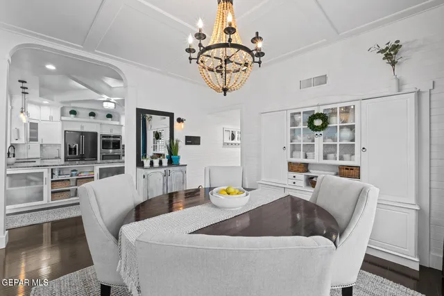 a living room with furniture a chandelier and a dining table with wooden floor