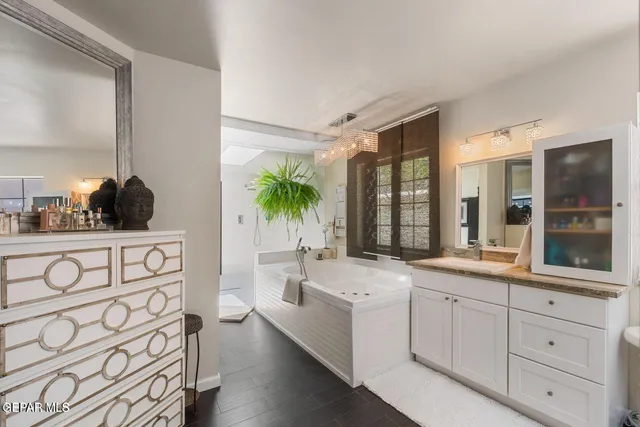 a large white kitchen with a sink and large mirror