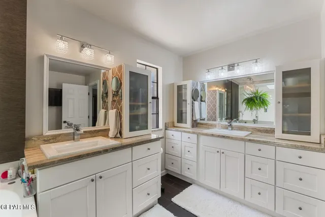 a bathroom with double sink large mirror and a window