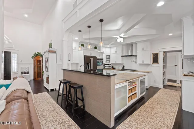 a kitchen with stainless steel appliances granite countertop a stove top oven a sink a refrigerator white cabinets and wooden floor