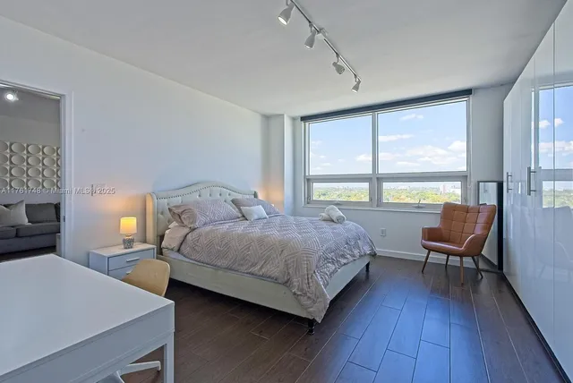 a bedroom with a bed a large window with wooden floor