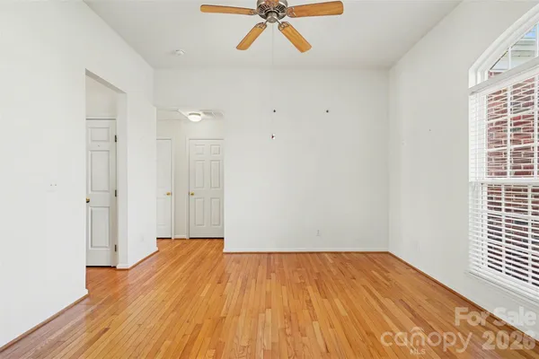 a view of a room with wooden floor a ceiling fan and windows