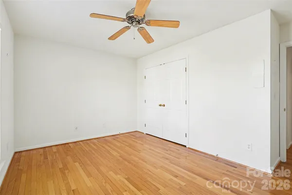 an empty room with a ceiling fan and wooden floor