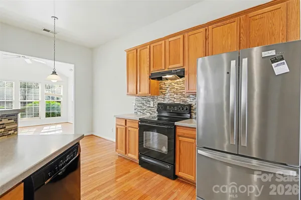 a kitchen with stainless steel appliances granite countertop a refrigerator a stove and a sink with wooden floor