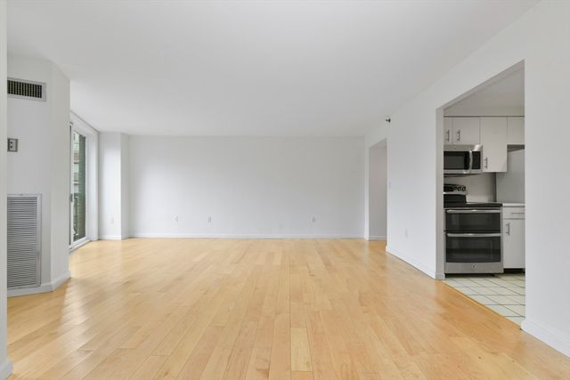a view of empty room with kitchen and window
