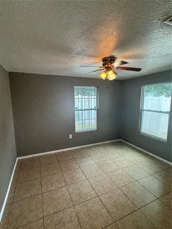 an empty room with windows and fan