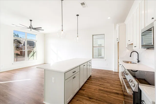 a view of a kitchen with kitchen island a sink wooden floor and white appliances