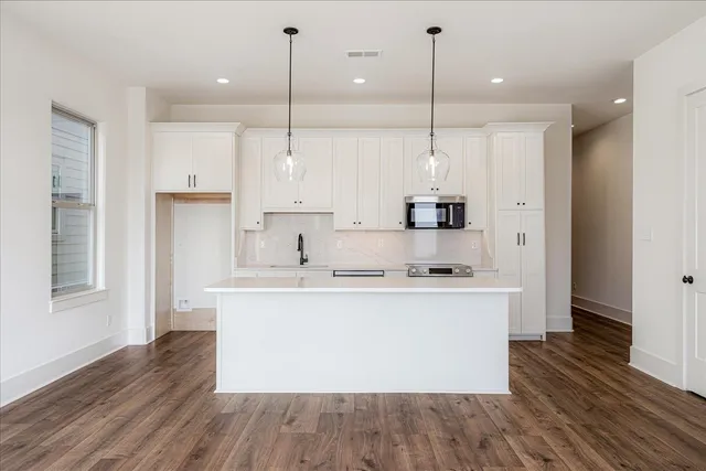 a kitchen with kitchen island white cabinets and wooden floor