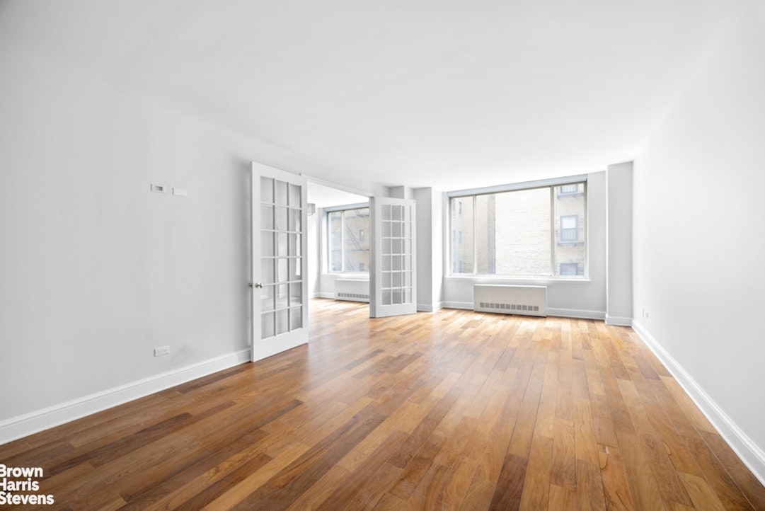 308 East 72nd Street, Unit 3D Manhattan, NY 10021 - Photo 2 of 8 an empty room with wooden floor and windows