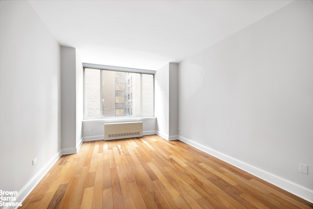 308 East 72nd Street, Unit 3D Manhattan, NY 10021 - Photo 6 of 8 a view of an empty room with wooden floor and a window