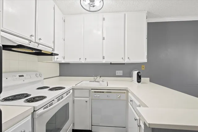 a view of cabinets a sink and a stove in a white cabinet