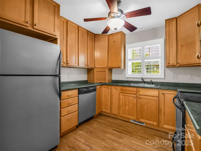 a kitchen with stainless steel appliances granite countertop a refrigerator a sink dishwasher a stove with wooden cabinets and floor