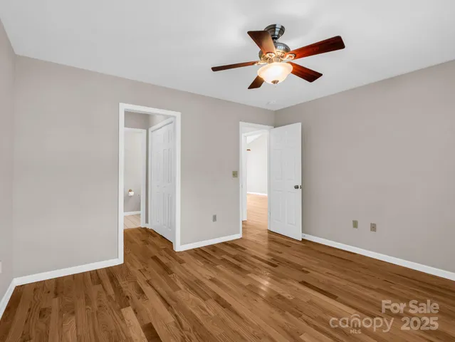 an empty room with wooden floor and ceiling fan