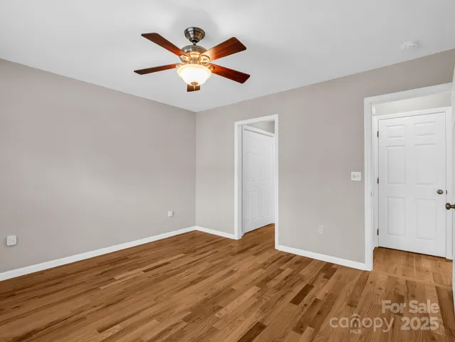 an empty room with wooden floor and a ceiling fan