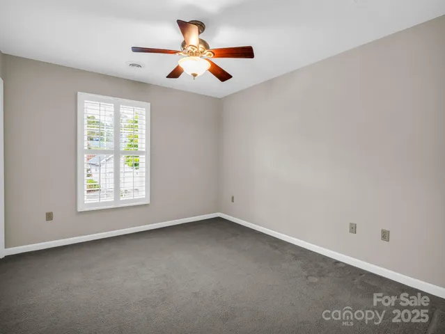 an empty room with ceiling fan and windows