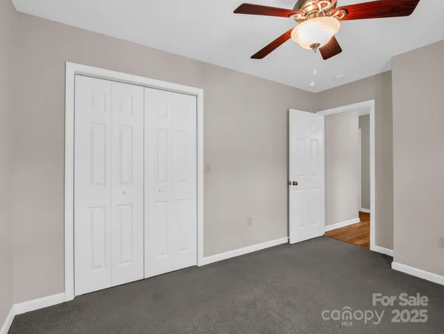 an empty room with closet and a chandelier fan