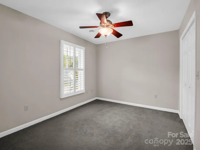 an empty room with ceiling fan and window