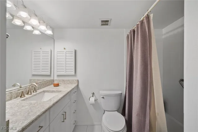a bathroom with a granite countertop sink toilet and shower curtains