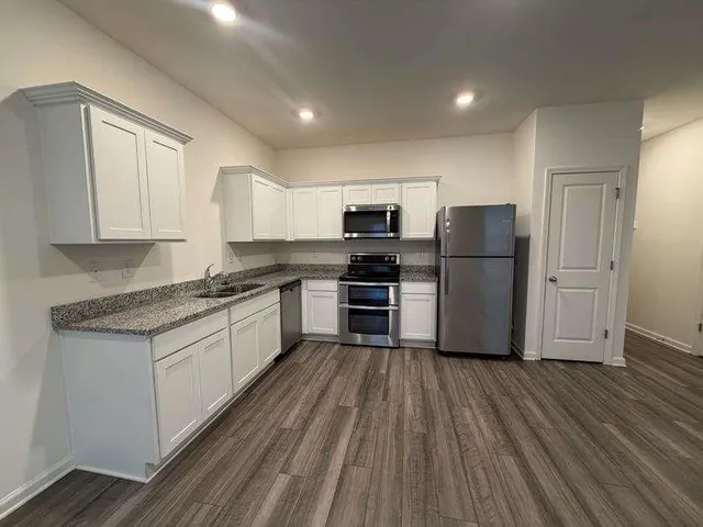 a kitchen with a refrigerator a stove top oven and wooden floors