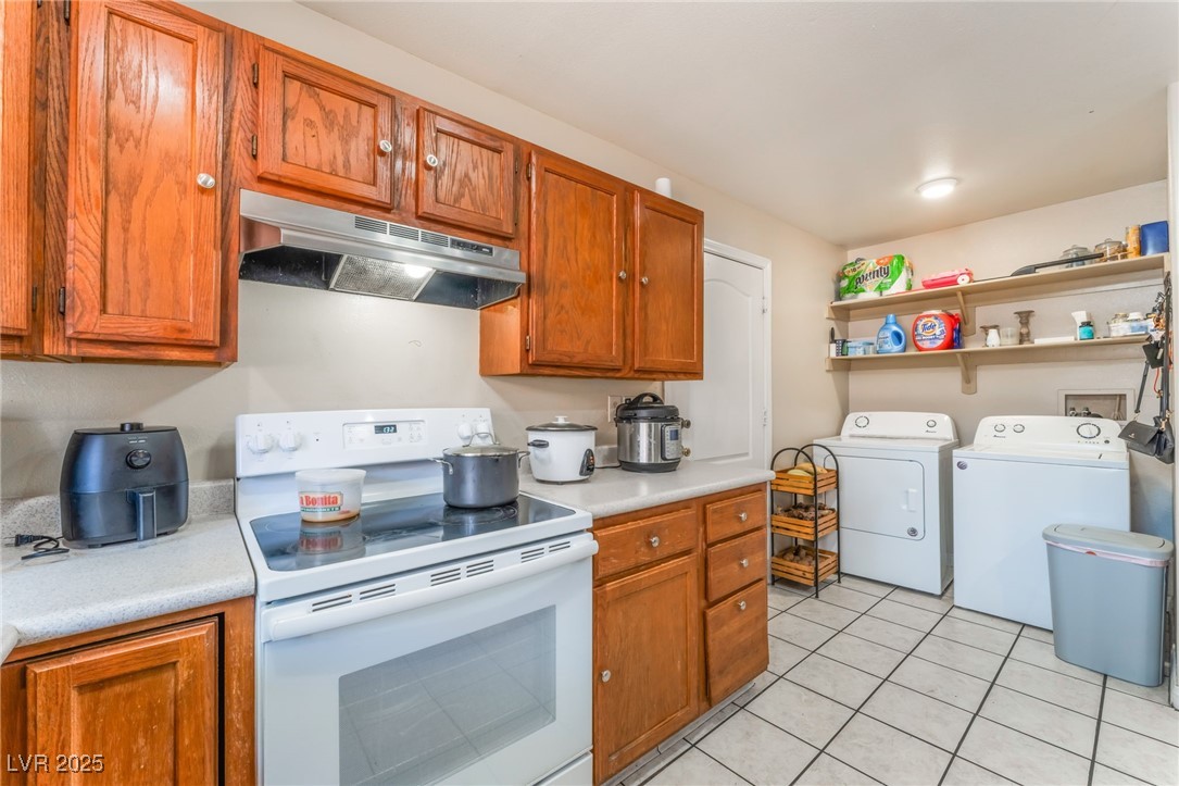 4656 East Desert Inn Road Las Vegas, NV 89121 - Photo 69 of 98 4652 E DI Kitchen with white range with electric cooktop, under cabinet range hood, washer and dryer, light countertops, and light tile patterned floors
