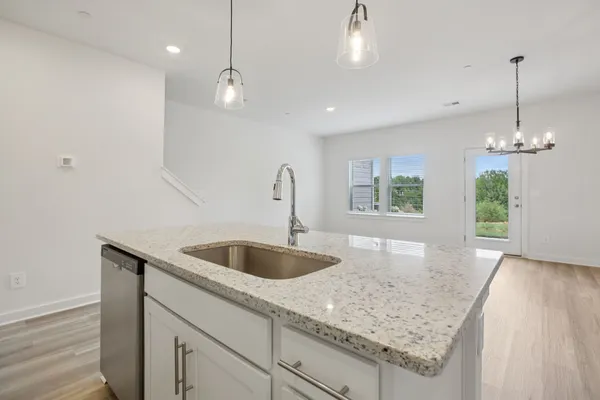 a kitchen with a sink chandelier and wooden floor