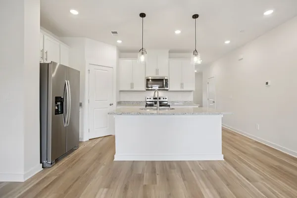 a large kitchen with stainless steel appliances a large center island attached withe living room