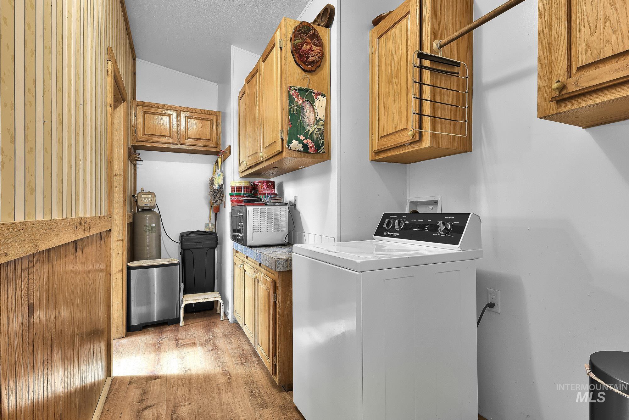 24900 Market Road Parma, ID 83660 - Photo 18 of 50 Utility room featuring wood-finish flooring, light wood cabinetry, and a countertop