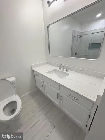 a spacious bathroom with a granite countertop toilet a sink and a mirror