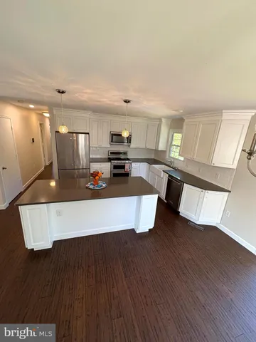 a large kitchen with kitchen island a large counter top space a sink stainless steel appliances and cabinets