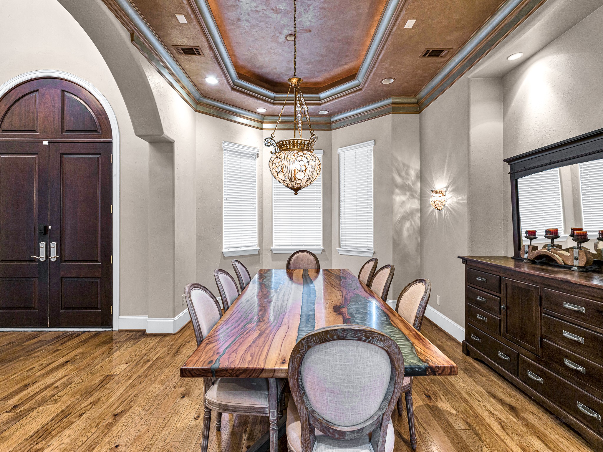 4614 Inker Street Houston, TX 77007 - Photo 5 of 36 This elegant dining room features a decorative ceiling with a central chandelier, and rich wood flooring. The space is illuminated by natural light from multiple windows, complemented by wall sconces for ambient lighting.