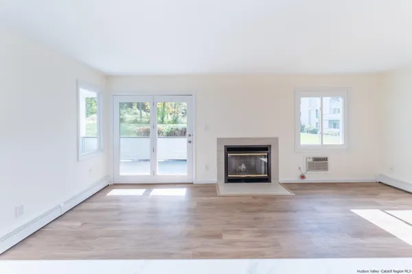 an empty room with windows and fireplace