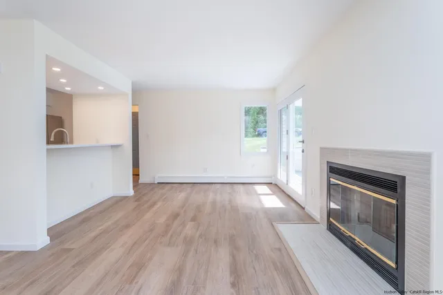 an empty room with wooden floor a fireplace and windows