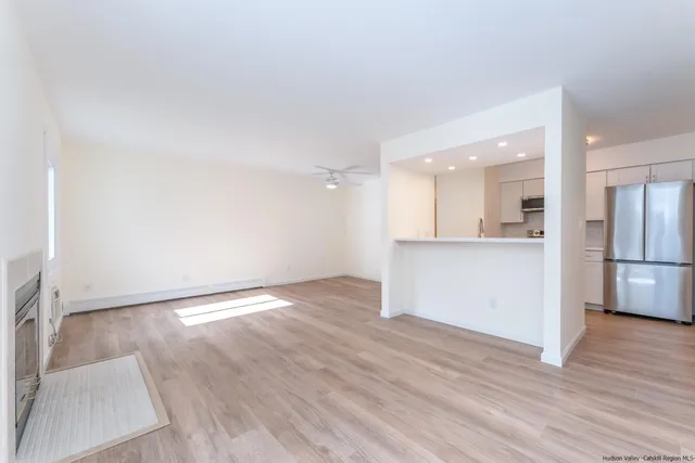 an empty room with wooden floor and kitchen view