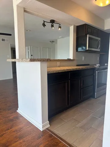 a kitchen with stainless steel appliances granite countertop a stove a sink and a microwave