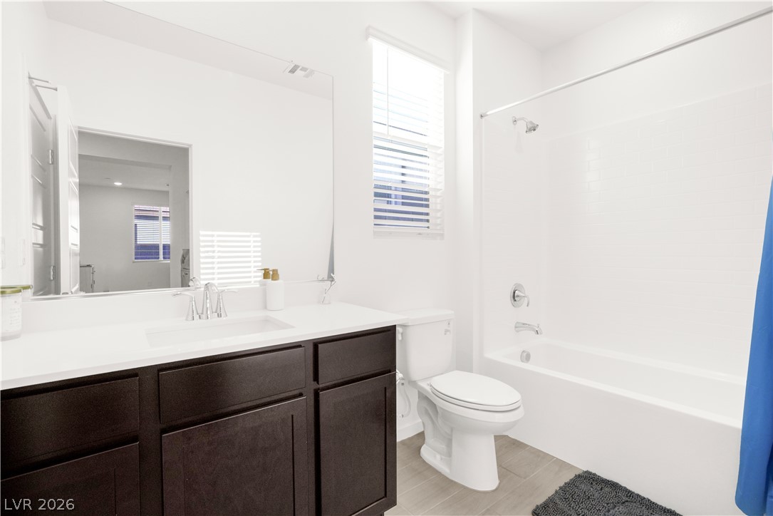 9398 Noble Fir Rdg Court Las Vegas, NV 89143 - Photo 20 of 36 A well-appointed bathroom features a single vanity, a modern toilet, and a pristine bathtub with an overhead shower.