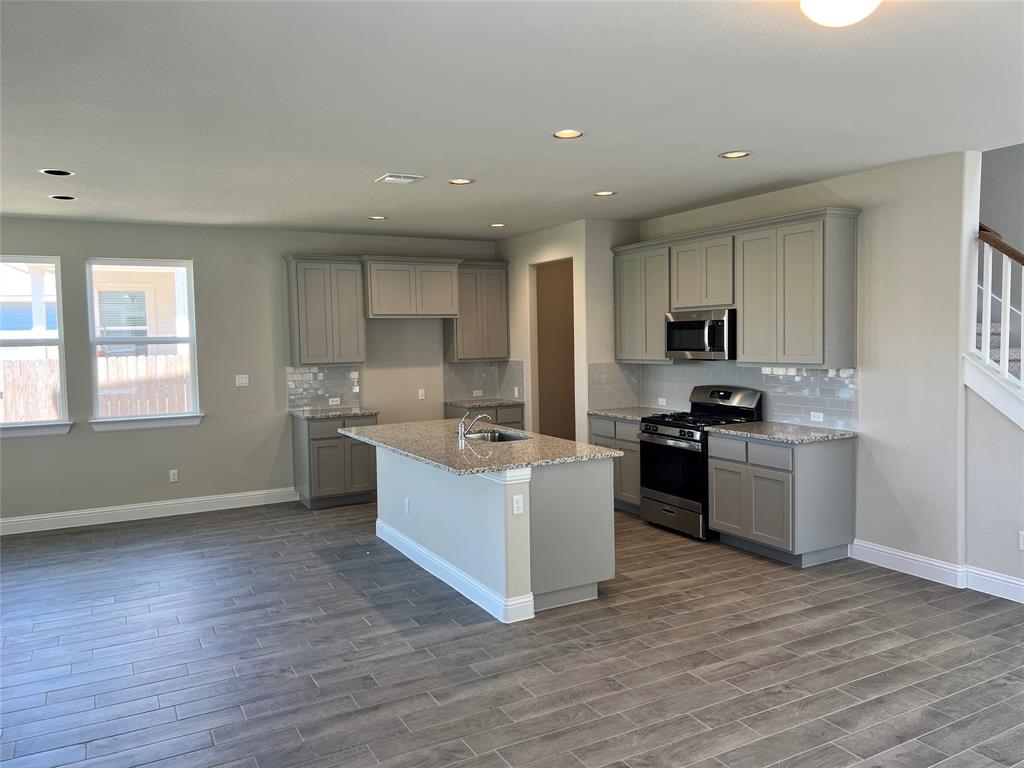 128 Free Stone Drive Georgetown, TX 78628 - Photo 6 of 29 Open-concept kitchen featuring light cabinetry, stainless steel appliances, granite countertops, and a subway tile backsplash