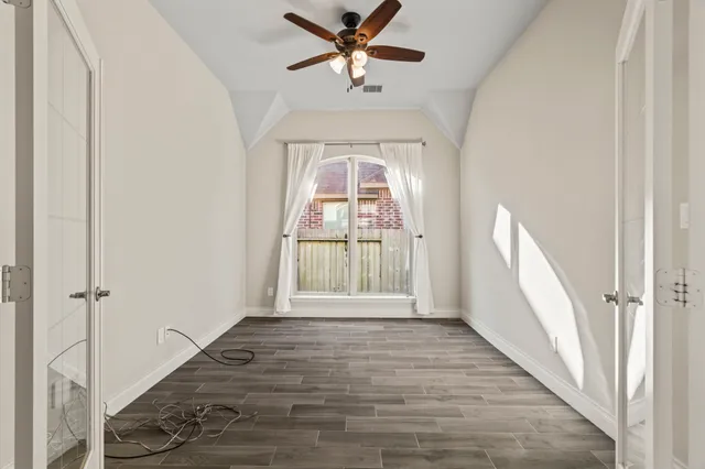 an empty room with wooden floor cabinet and windows