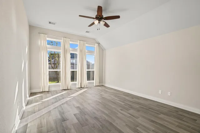 a view of a room with wooden floor and ceiling fan
